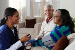 The caregiver checks the blood pressure of the old woman