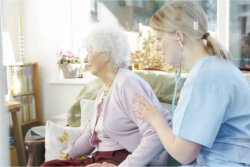 The caregiver helps the old woman to sit